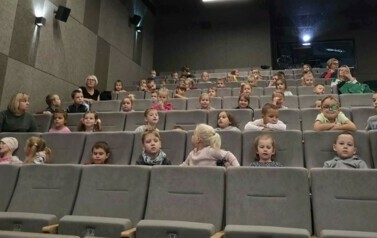 Dzieci siedzą w kinie i czekają na seans