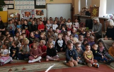 Dzieci siedzą na dywanie i czekają na występ
