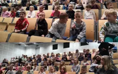 Dzieci siedzą na krzesłach i czekają na występ