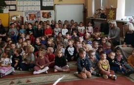 Dzieci siedzą na dywanie i czekają na występ